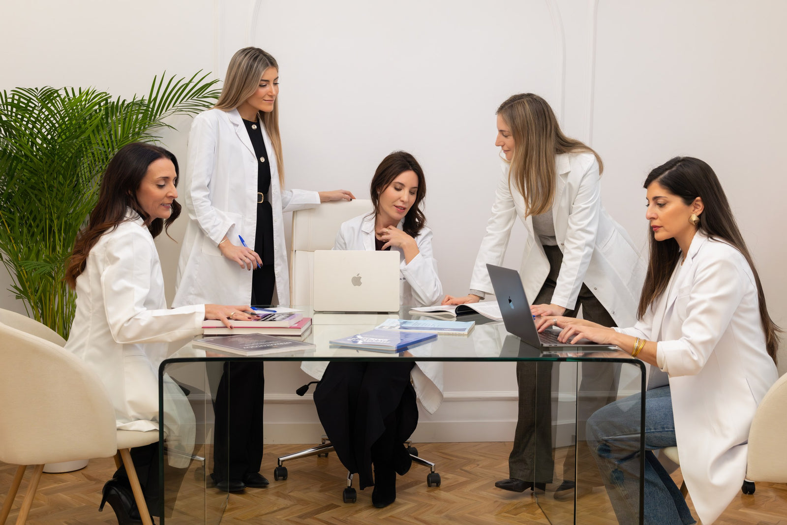 Cinco doctoras del equipo de Esthea Medica, trabajando juntas en la mesa de reuniones de la clínica